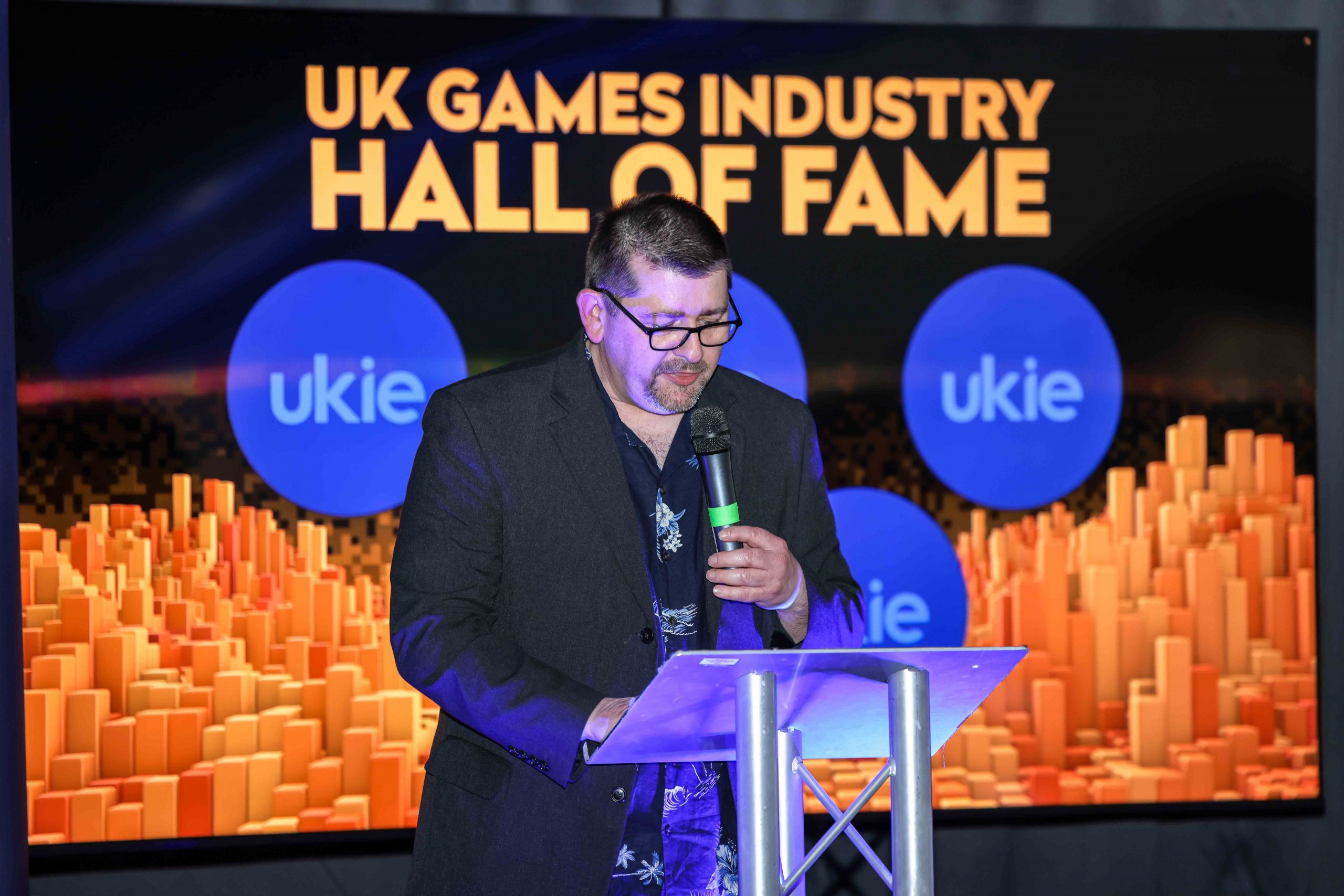 Sam Woods at the UK Games Industry Hall of Fame with Ukie logo in background